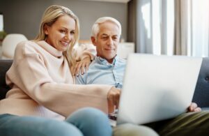 A man and woman on a couch, engaged with a laptop, possibly reviewing information from a Pittsburg periodontist.
